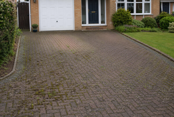 Block paving driveway in Bedford before cleaning with weeds growing through the joints