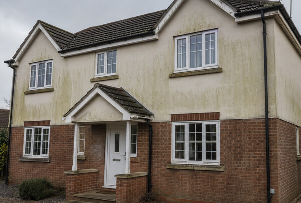 Bedford house exterior before cleaning with marked lower walls, porch details and stained side areas