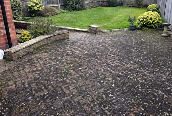 Block paving patio in Northampton before cleaning, with moss growth and dark staining