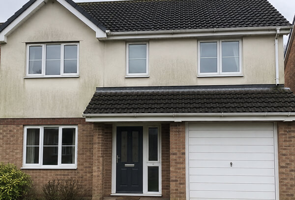 Exterior wall in Luton before cleaning with green staining around windows and gutter line