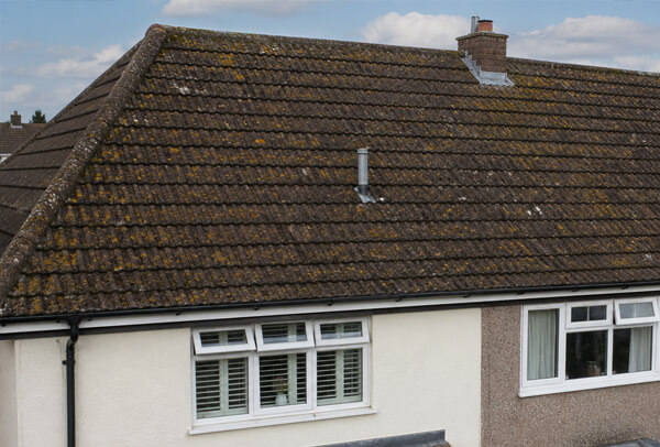 Roof in Luton before cleaning, with moss and weather staining visible on the tiles