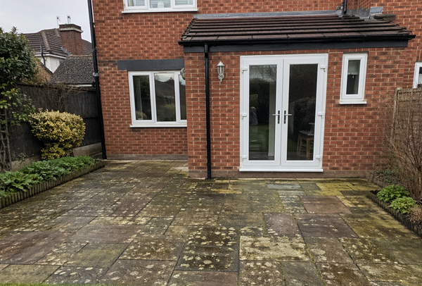 Block paving patio in Northampton before cleaning and re-sanding, with debris in the joints