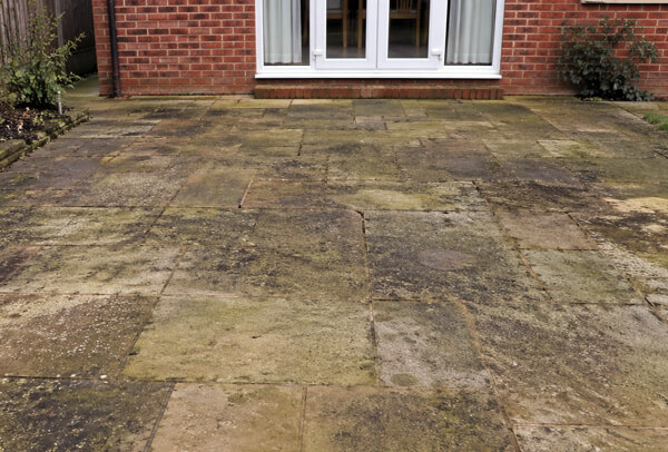 Sandstone patio in Northampton before cleaning, with staining and dull surface colour