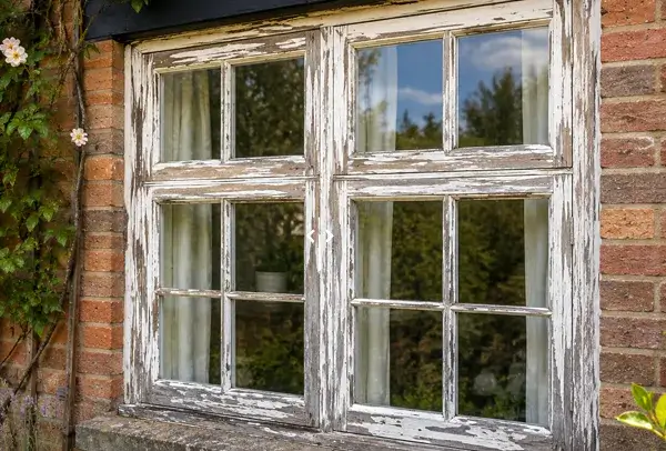 Timber window frame before painting with weathered woodwork and tired old paint